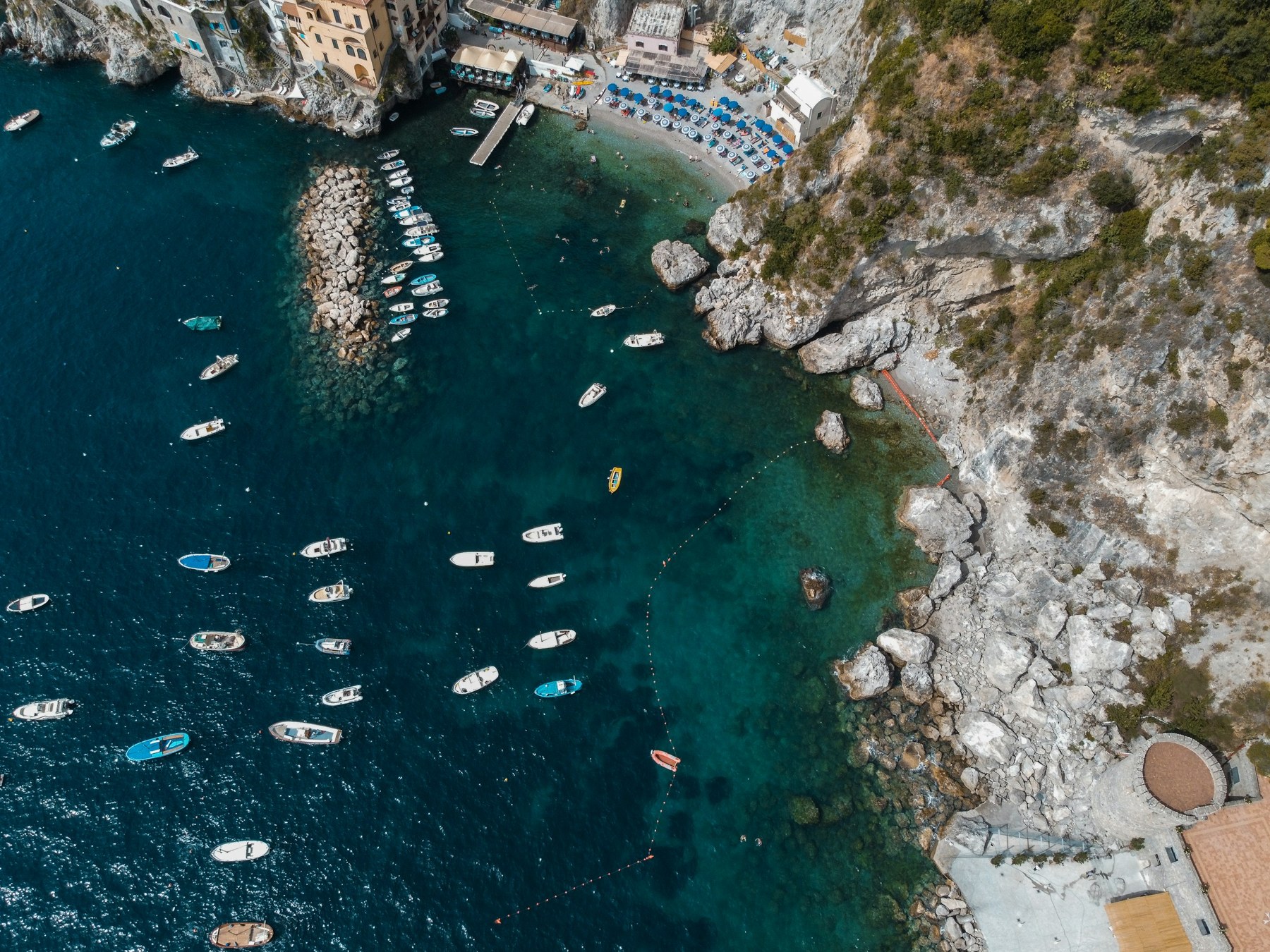 Boats beside Mediterranean coastal cliffs